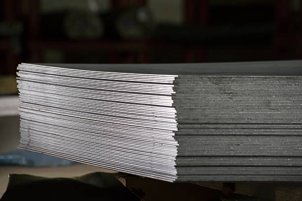 Stainless steel pipes, bars and sheets of metal,  deposited in stacks in a industrial warehouse